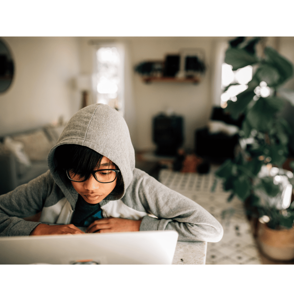 Boy in hooded top looking at the laptop