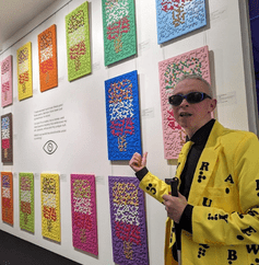 Clarke Reynolds - Braille Artist standing in front of his artworks.