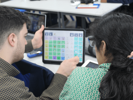 Specialist Teaching Assistant James Dewar-Hassan supporting a student with their AAC device.