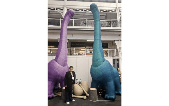 Advisory Teacher Maureen with two towering dinosaurs Advisory Teacher Maureen with two towering dinosaurs