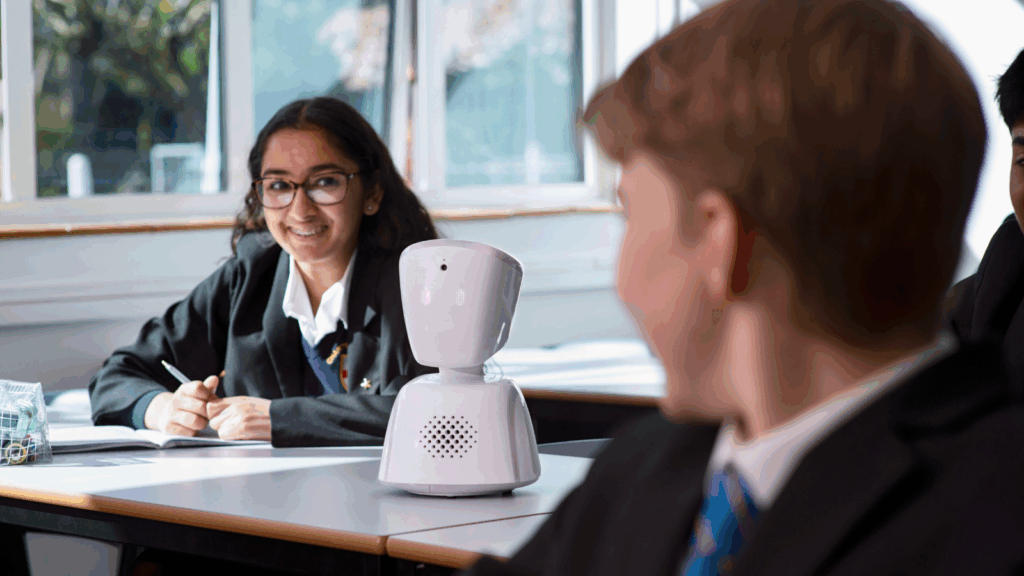 AV1 robot sitting in the place of a student in the classroom with other students sitting at their desks. AV1 robot sitting in the place of a student in the classroom with other students sitting at their desks.